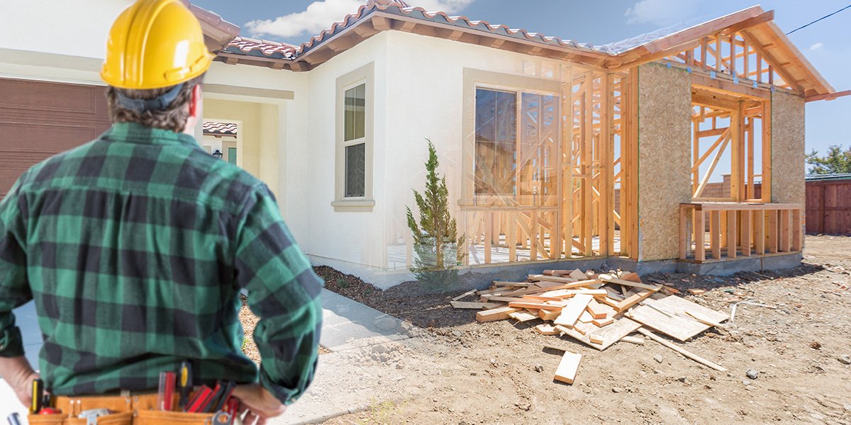 Contractor Standing Outside Construction Framing and Photo of New House.